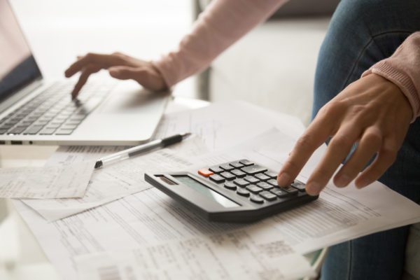 Woman's hands using calculator and laptop.